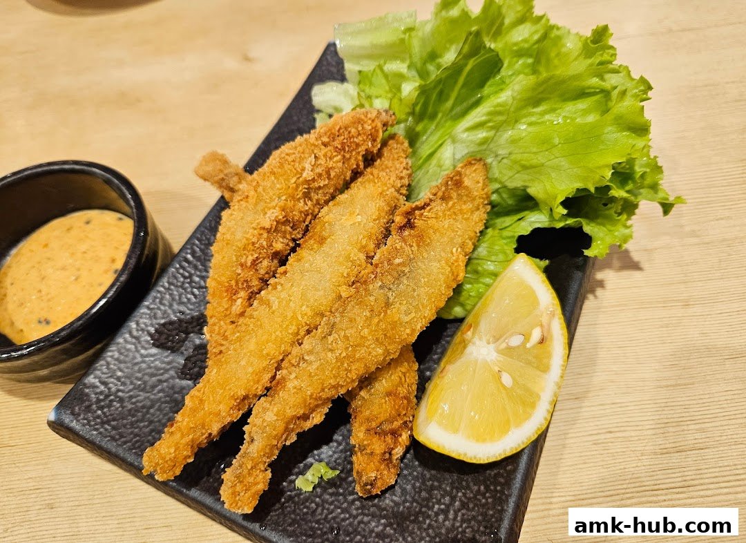 Crispy fried fish served with dipping sauce, lettuce, and a lemon wedge.