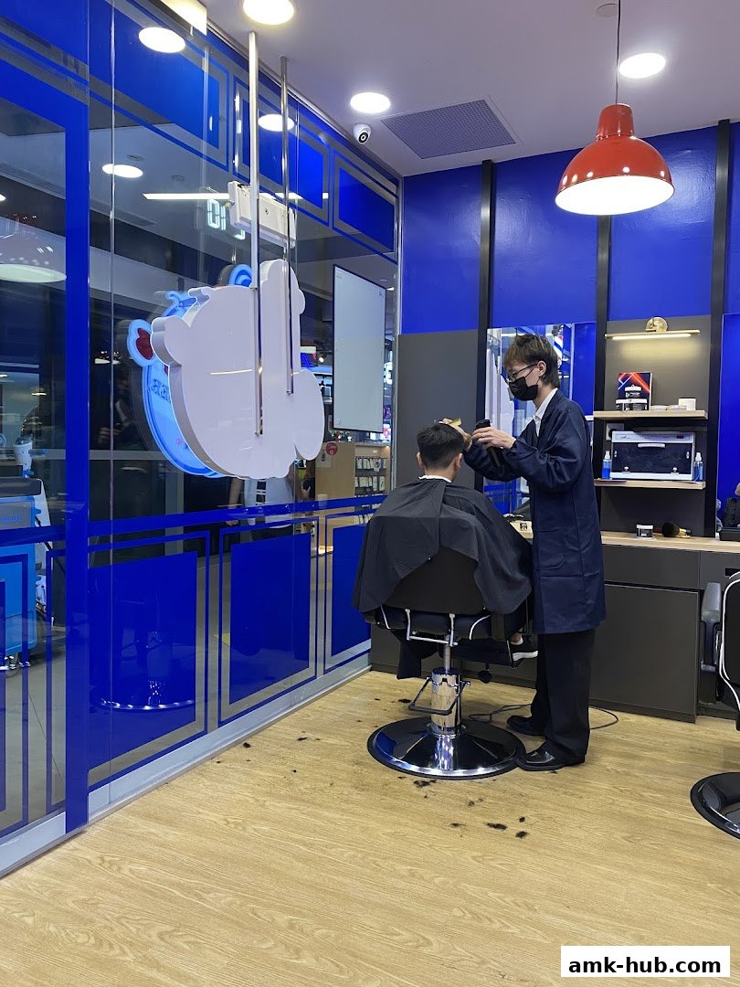 A barber is cutting a customer's hair inside a modern barbershop with blue accents.