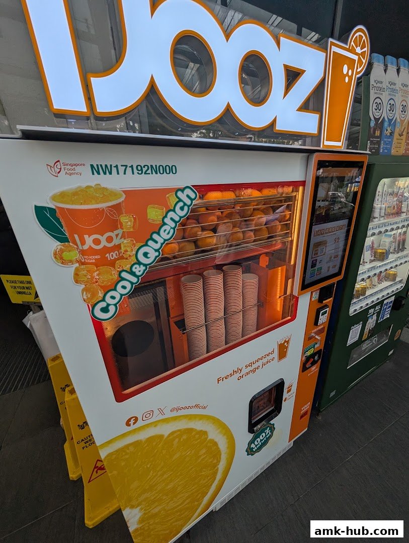 An iJooz vending machine offering freshly squeezed orange juice with oranges visible inside.