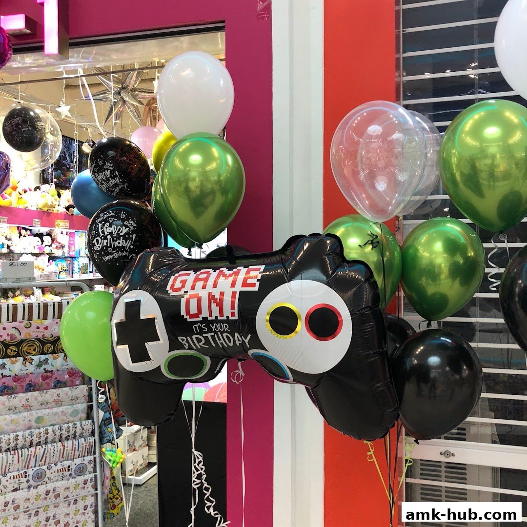 A display of balloons, including a large controller-shaped balloon, in a retail store.