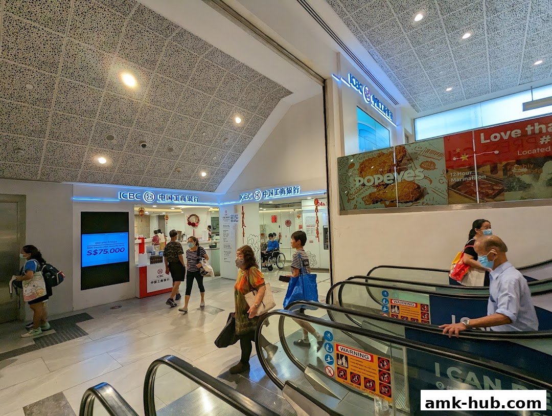 People walking past an ICBC bank branch and a Popeyes restaurant advertisement.