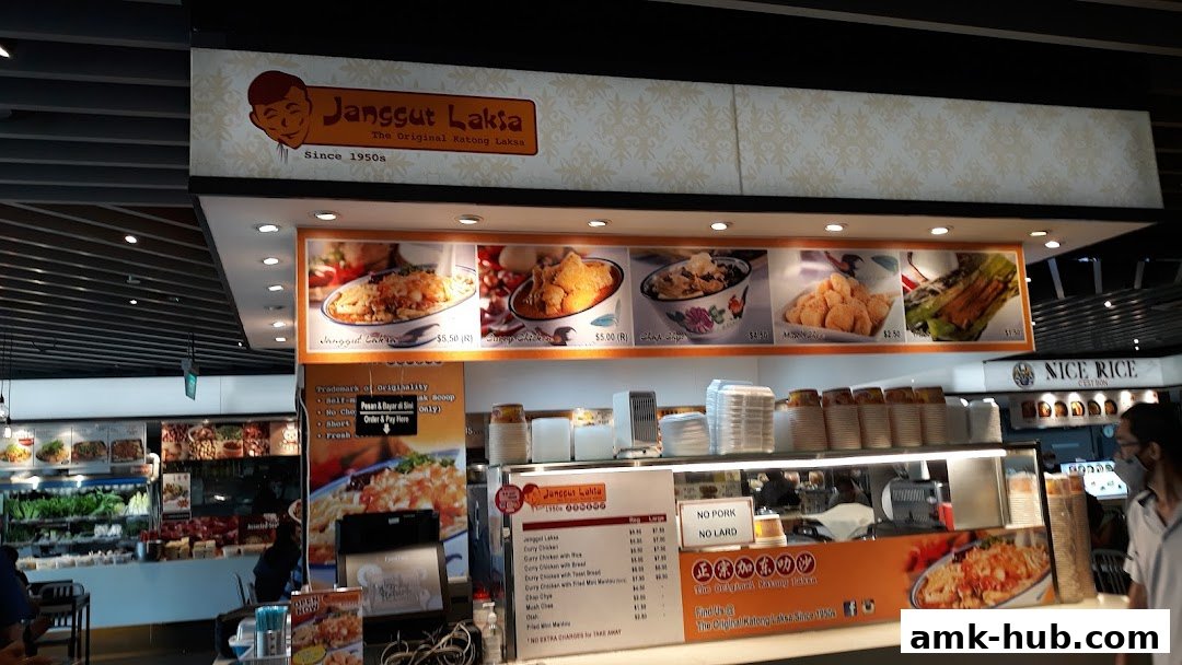 The exterior of a Kopitiam shop called Janggut Laksa, featuring food images and a menu.