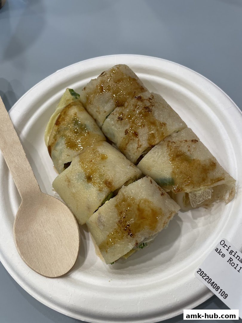 A plate of sliced spring rolls with a wooden spoon and a label.