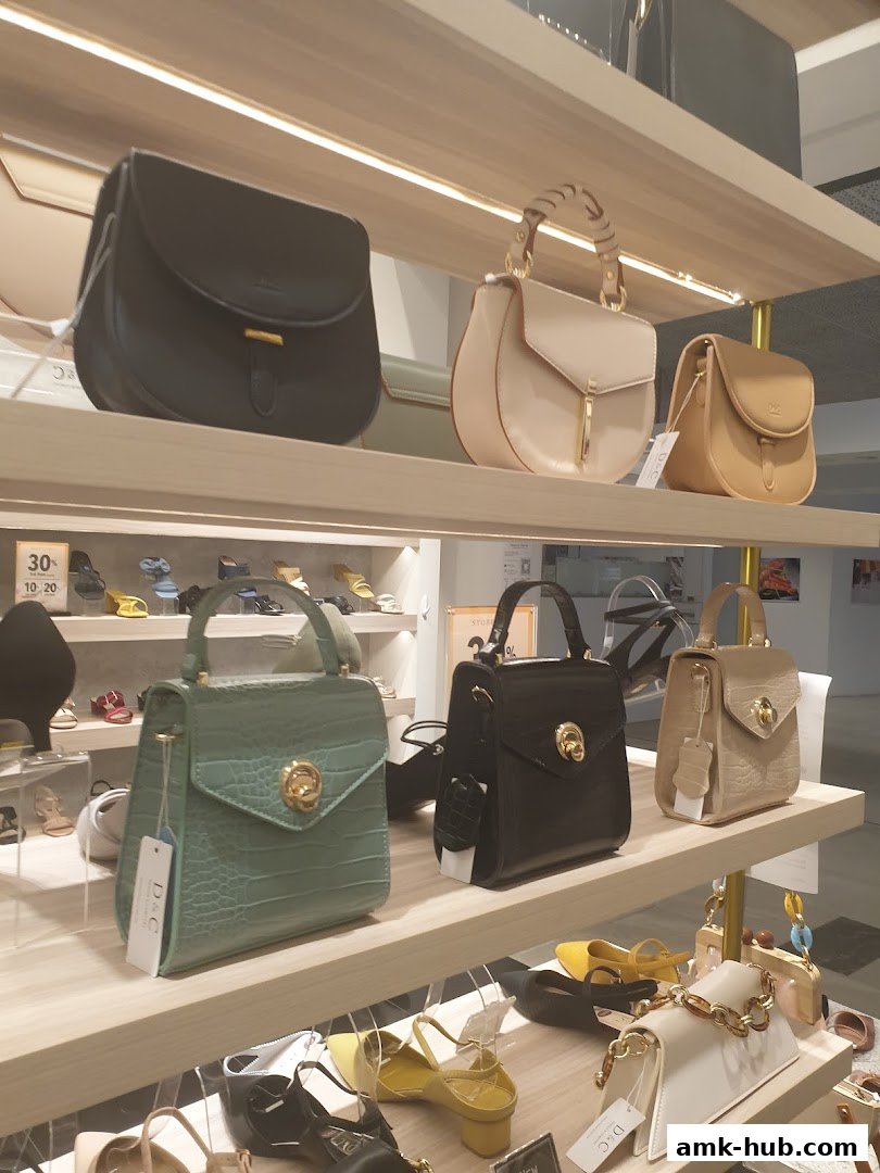 A display of various handbags and shoes on shelves in a retail store.