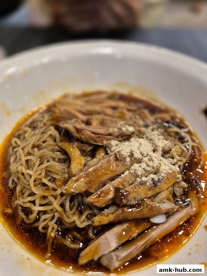 A close-up shot of a bowl of noodles topped with sliced meat and a savory sauce.