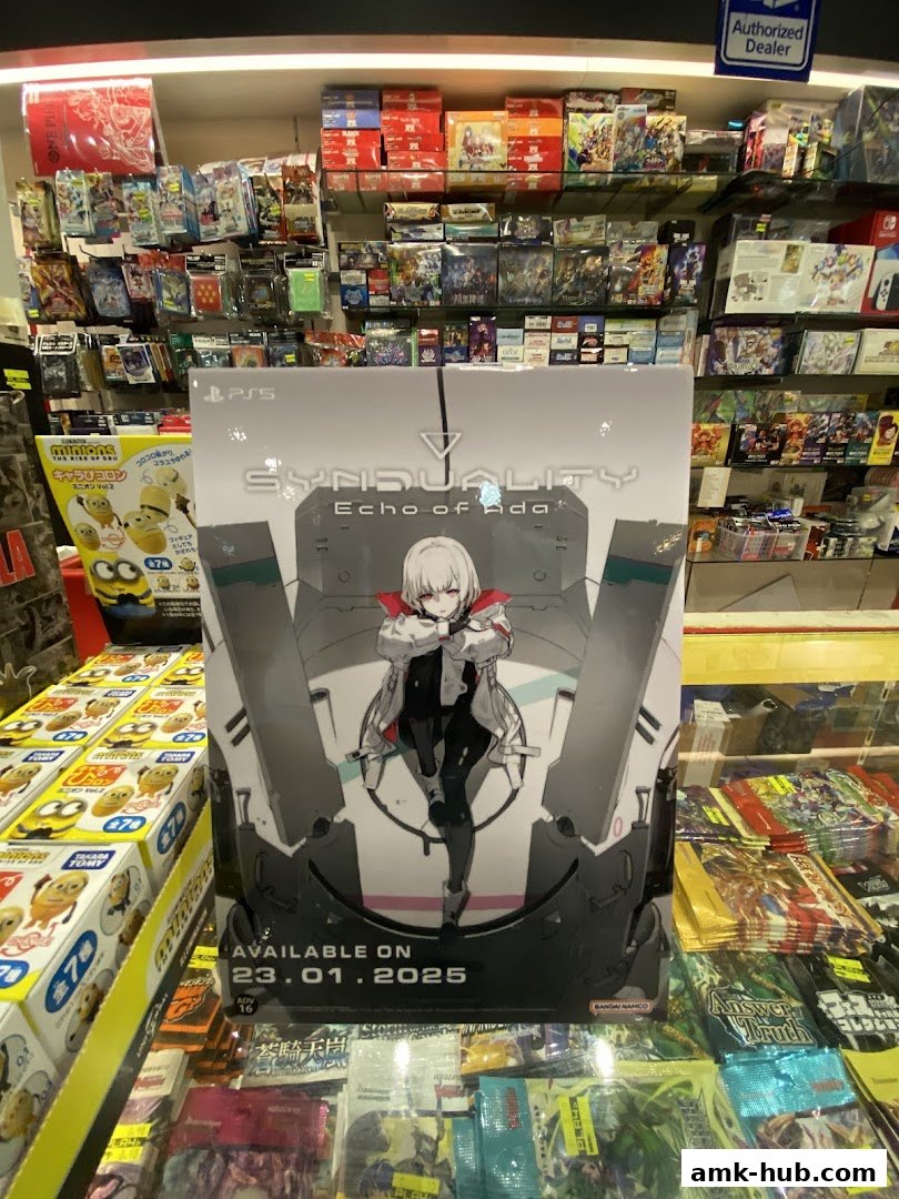 A display stand for the game SYNDUALITY: Echo of Ada, with shelves of games and merchandise in the background.