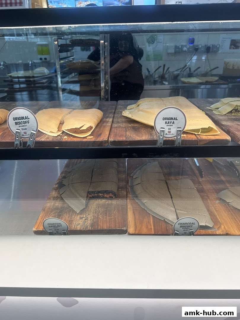 A display case filled with various types of pancakes, some sliced and labeled with flavors and prices.