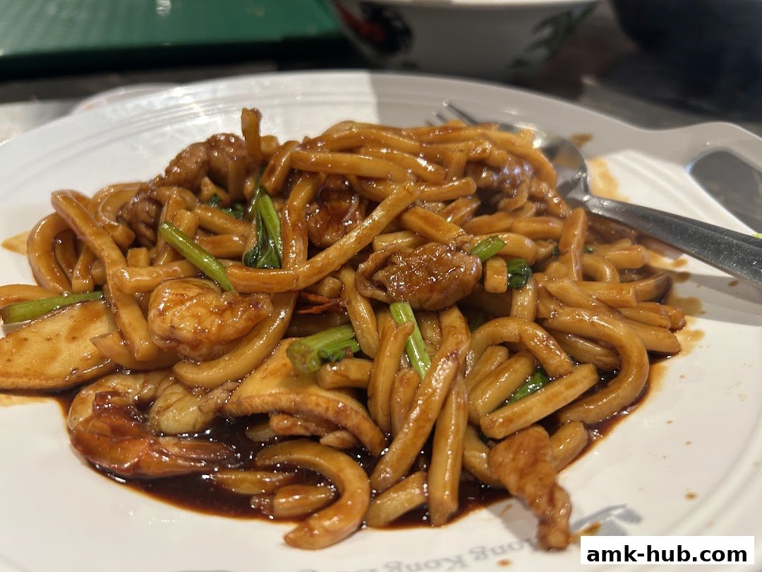 A plate of stir-fried noodles with shrimp, meat, and vegetables.