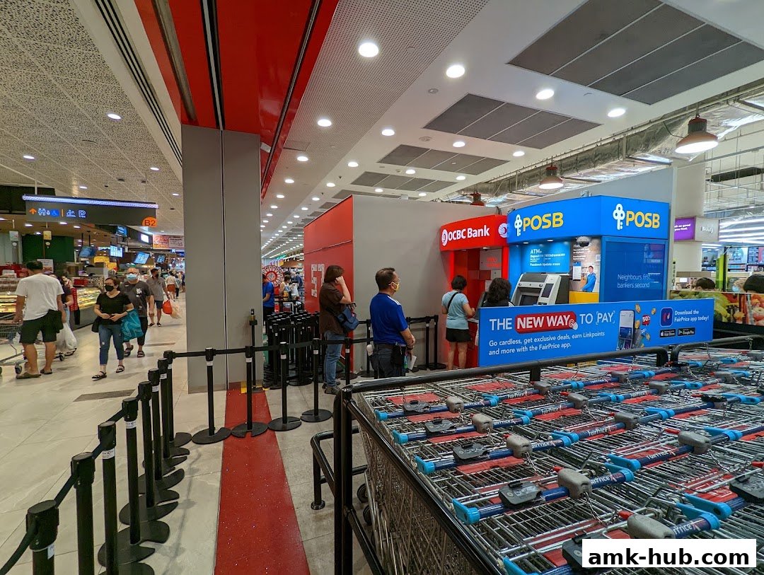 An OCBC Bank and POSB ATM service area with a queue of customers inside a FairPrice Xtra supermarket.