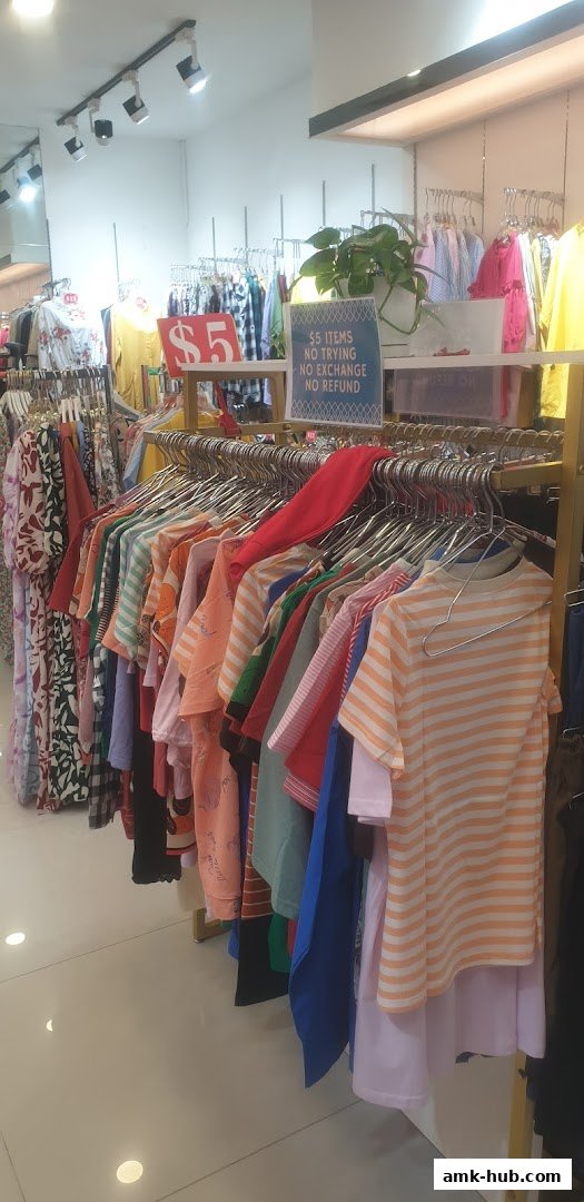 A clothing store interior with racks of colorful children's apparel and a '$5' sale sign.