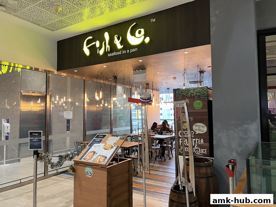 The entrance to Fish & Co. restaurant, featuring its illuminated sign and indoor seating.