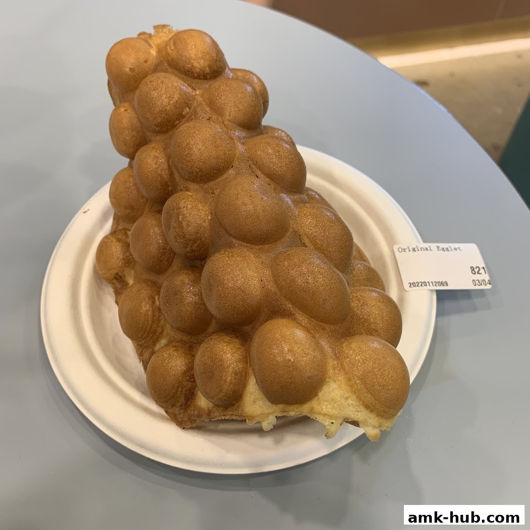 A close-up of a golden-brown bubble waffle served on a white plate.