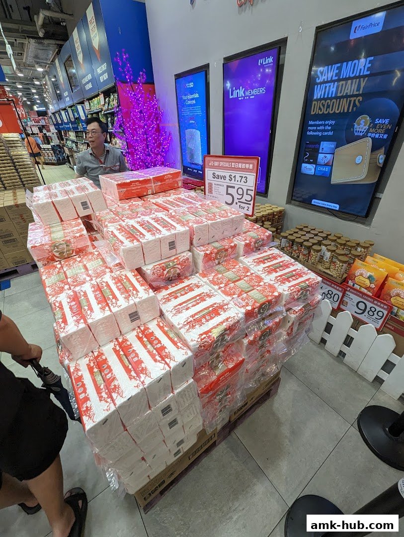 A display of packaged napkins with a promotional sign and digital screens in a supermarket.