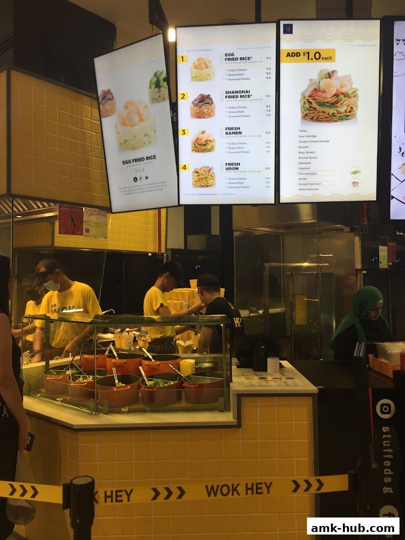 A brightly lit Wok Hey counter displaying a menu with various rice and noodle dishes.