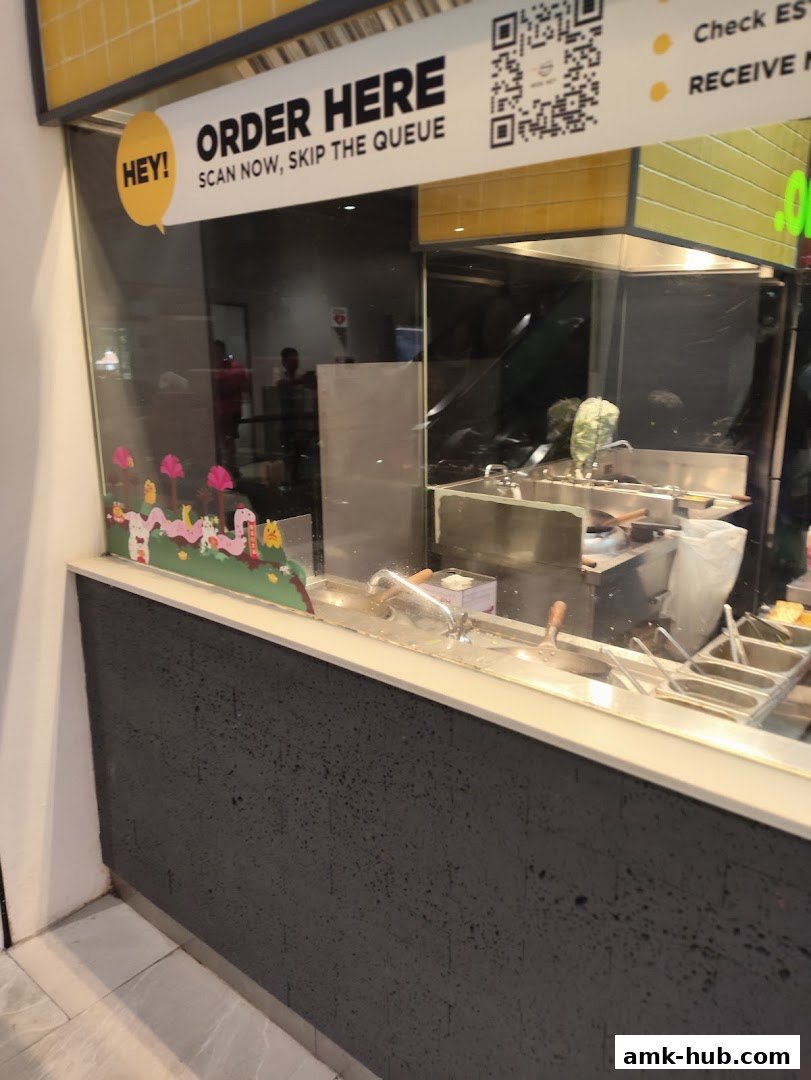 A shop counter with an 'Order Here' sign and a QR code for scanning.