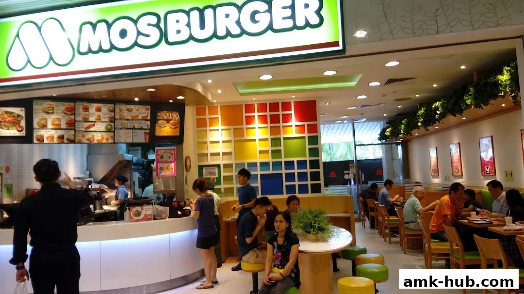 Interior view of a MOS Burger restaurant with customers and a colorful wall.