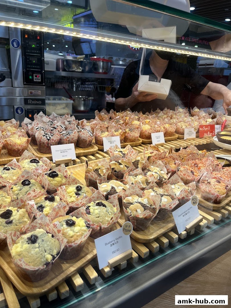 A display of freshly baked muffins at Butter Cream Bakery, with various flavors and prices visible.