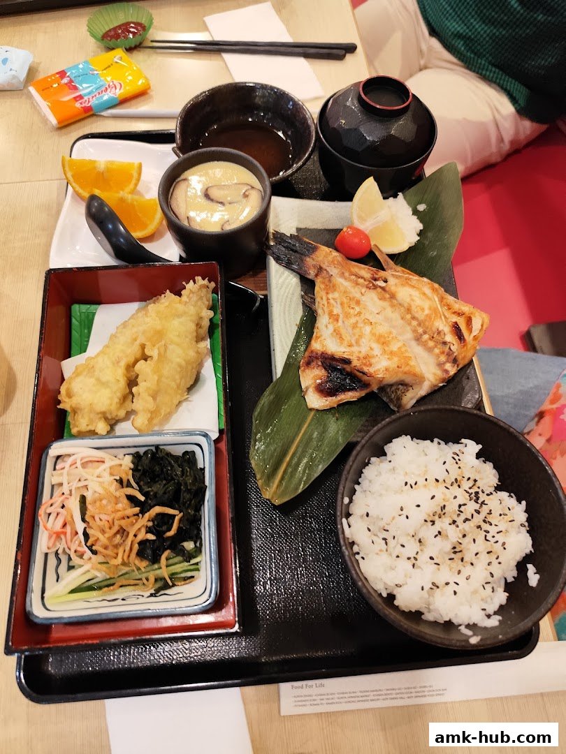 A delicious Japanese set meal featuring grilled fish, tempura, rice, and side dishes.