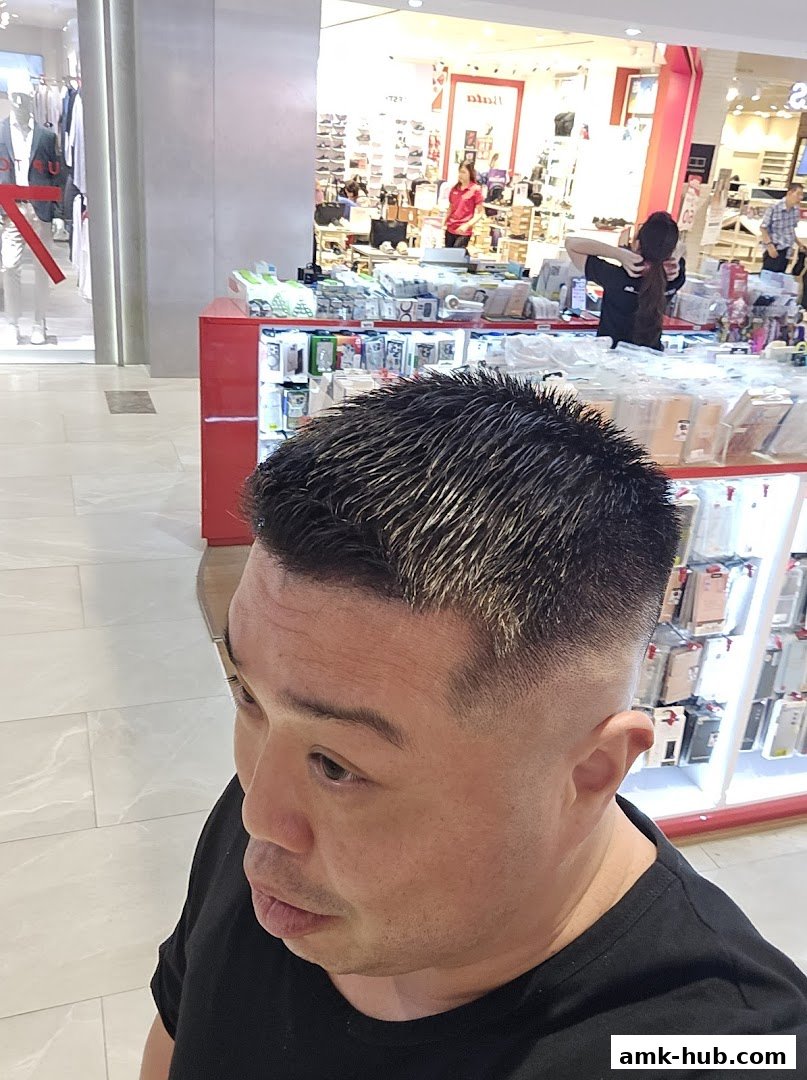 A man with a stylish fade haircut poses in front of a retail display.