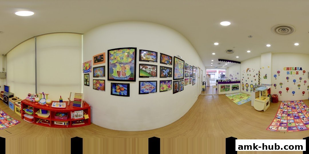 A bright and colorful classroom interior with children's artwork displayed on the walls and toys on the floor.