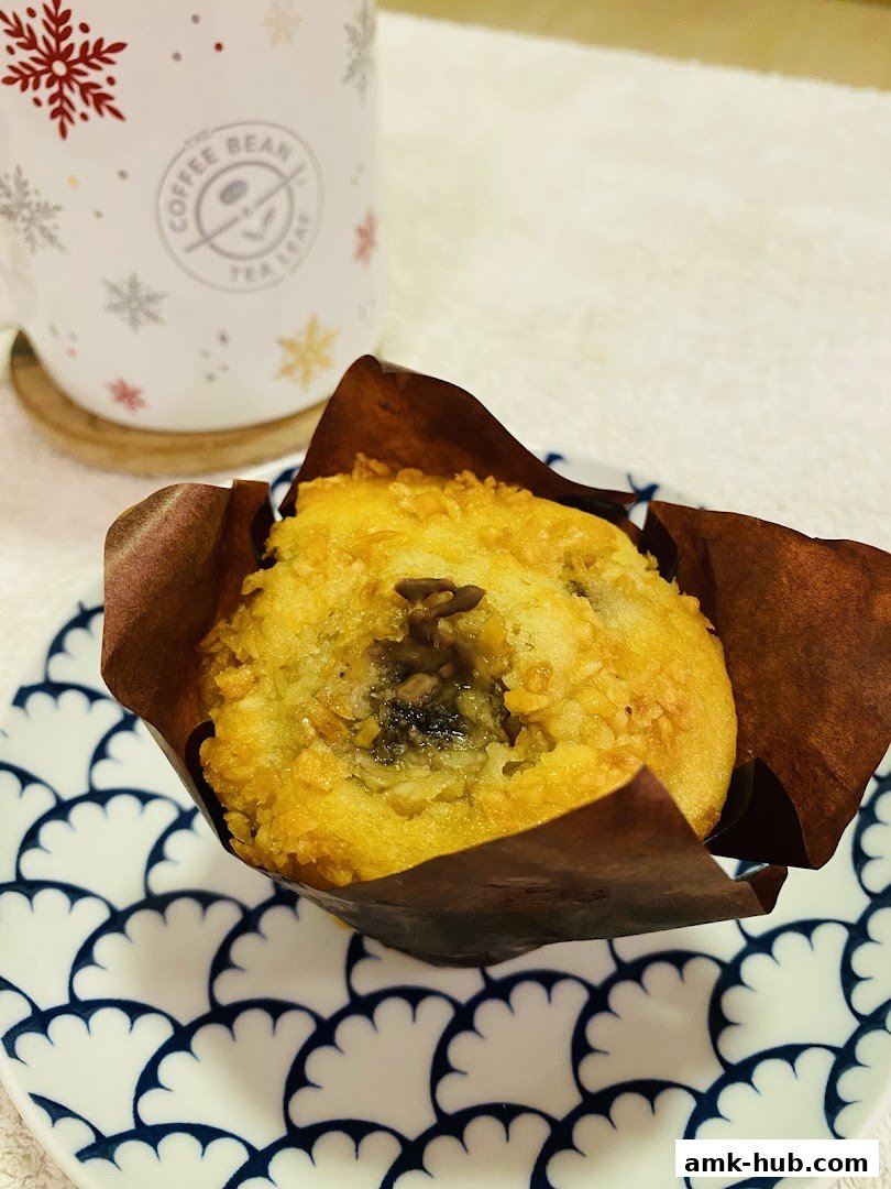 A close-up of a muffin on a decorative plate next to a coffee mug.