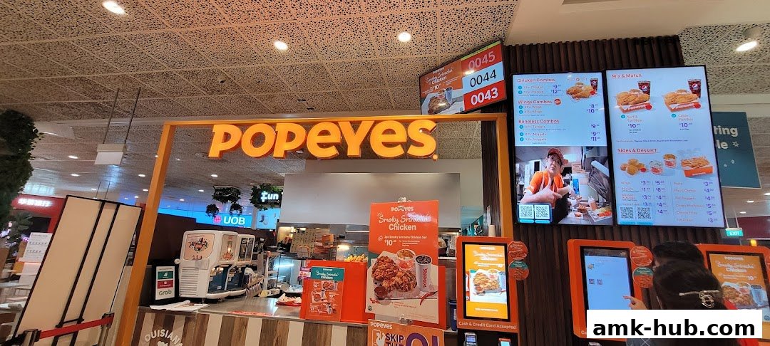 The Popeyes restaurant counter with digital menus displaying food items and prices.