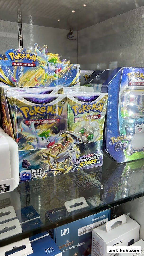 Display of Pokemon trading card game packs and boxes, along with other electronics.