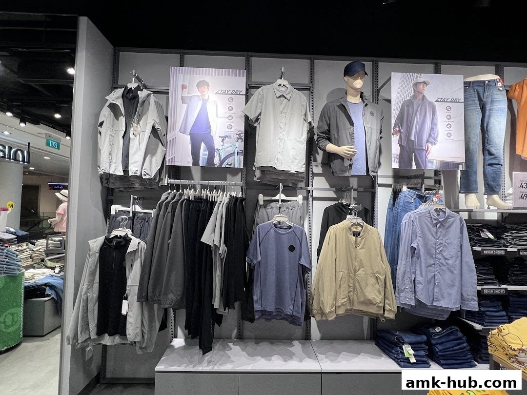 A display of men's casual wear, including jackets, shirts, and pants, with promotional posters.