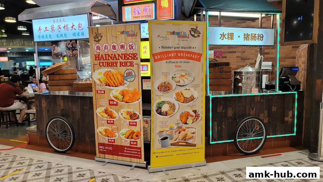 A food stall with promotional banners showcasing Hainanese Curry Rice and breakfast items.