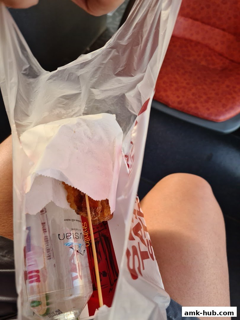 A person holding a Shihlin Taiwan Street Snacks bag with a fried snack and a bottle of water.
