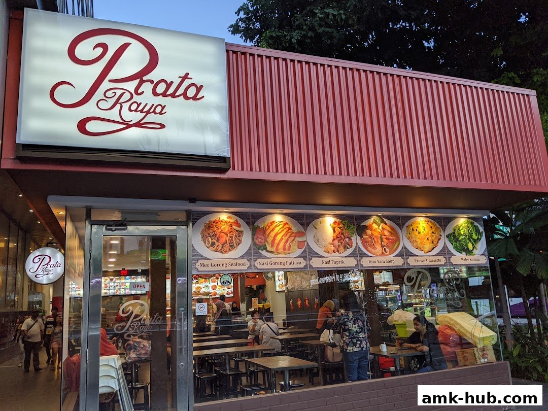 The exterior of Prata Raya restaurant with a prominent sign and food displays.