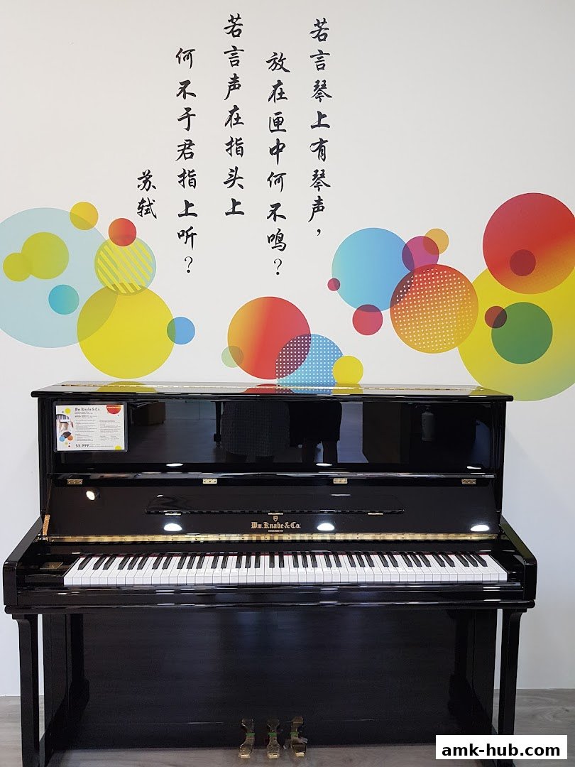 A black upright piano with Chinese calligraphy and colorful circles on the wall.