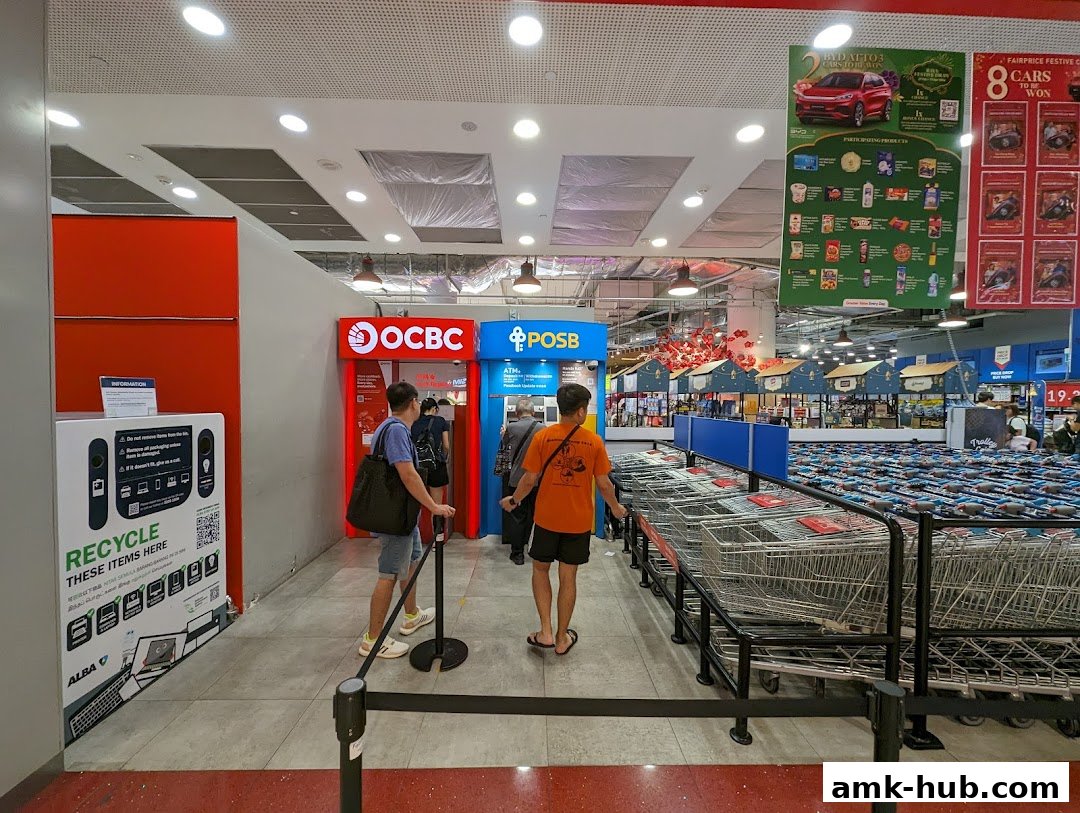 People queue at OCBC and POSB ATMs next to a recycling station and rows of shopping carts.