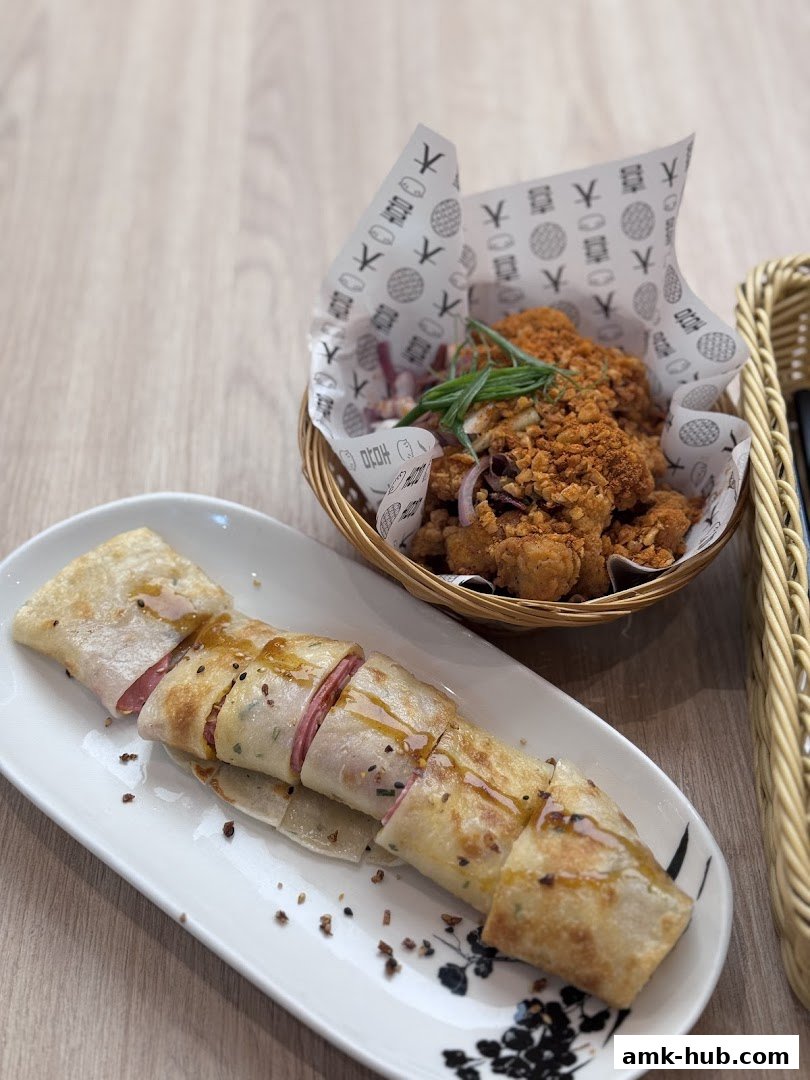 A close-up shot of two popular dishes from DaXi - AMK Hub, a savory wrap and crispy fried chicken.