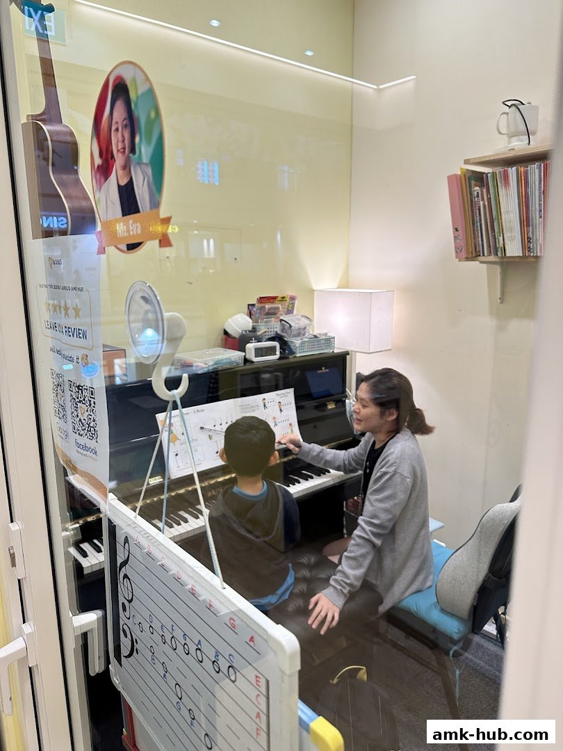 A music teacher instructs a young student on a piano, with educational materials visible.