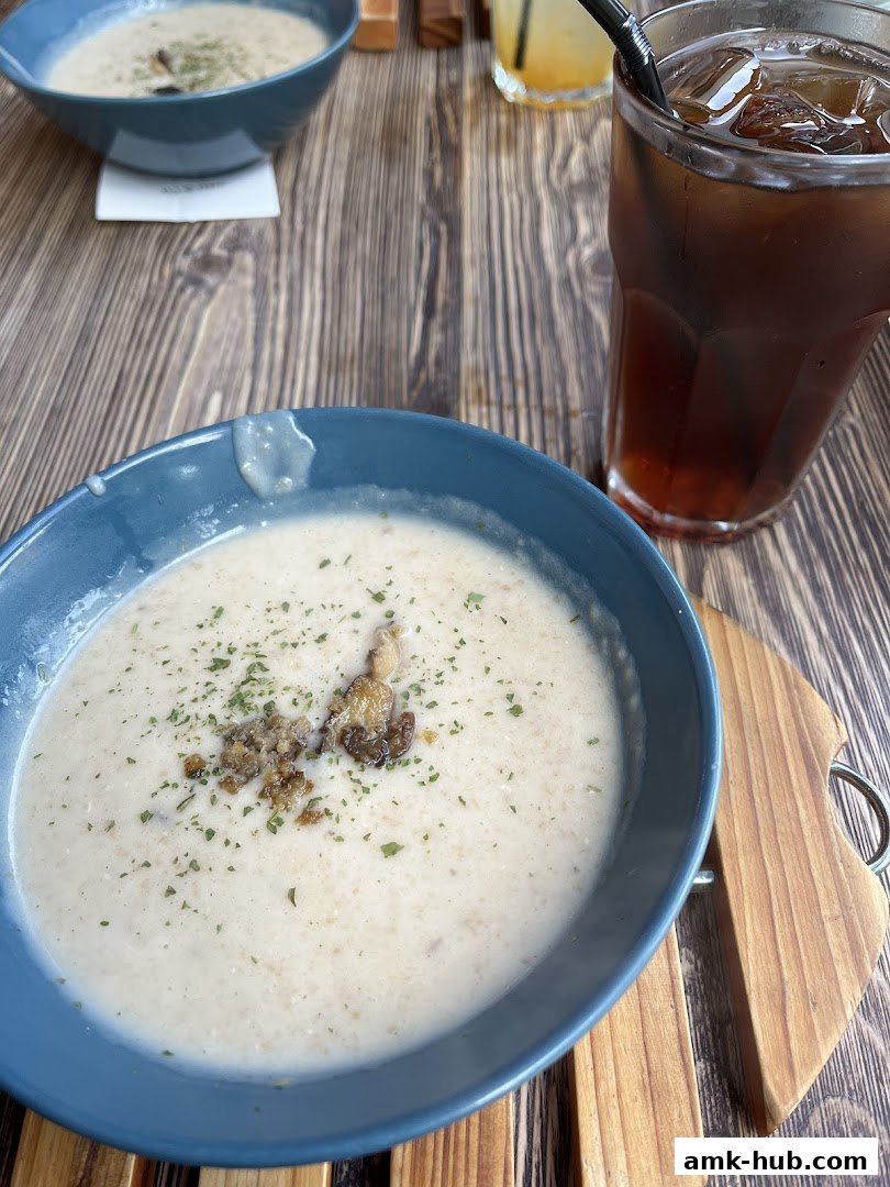 A close-up of creamy mushroom soup in a blue bowl with a drink on the side.