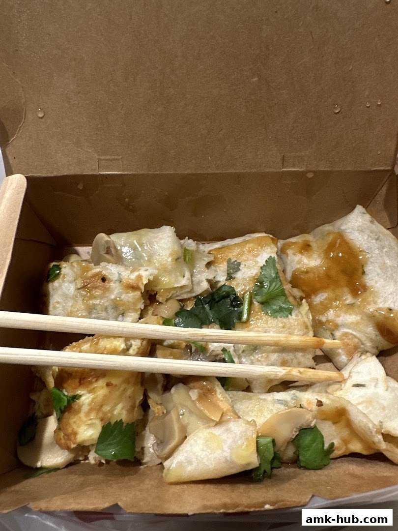 A close-up of Taiwanese street food, likely scallion pancakes, in a takeout box.