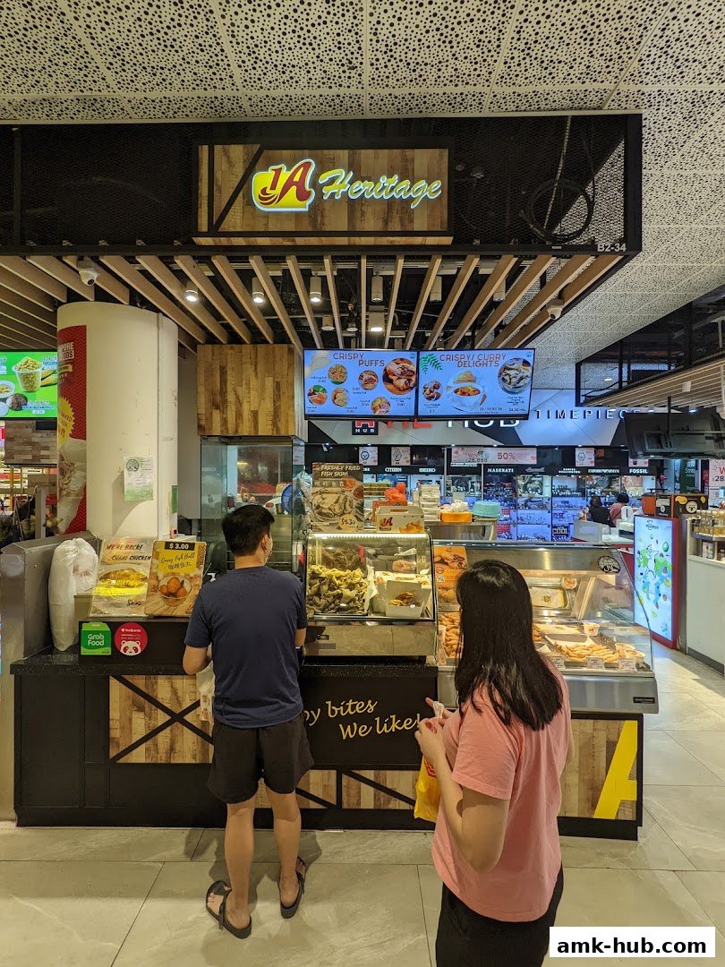 A couple orders food at a counter displaying various fried snacks and menu items.