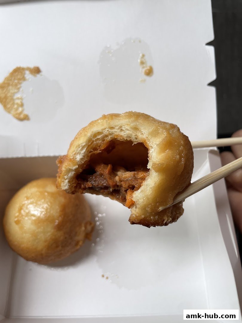 A close-up of a dim sum item being held by chopsticks, showing its crispy exterior and filling.