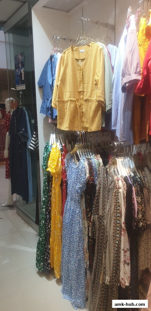 A display of colorful women's dresses and tops on hangers inside a retail store.