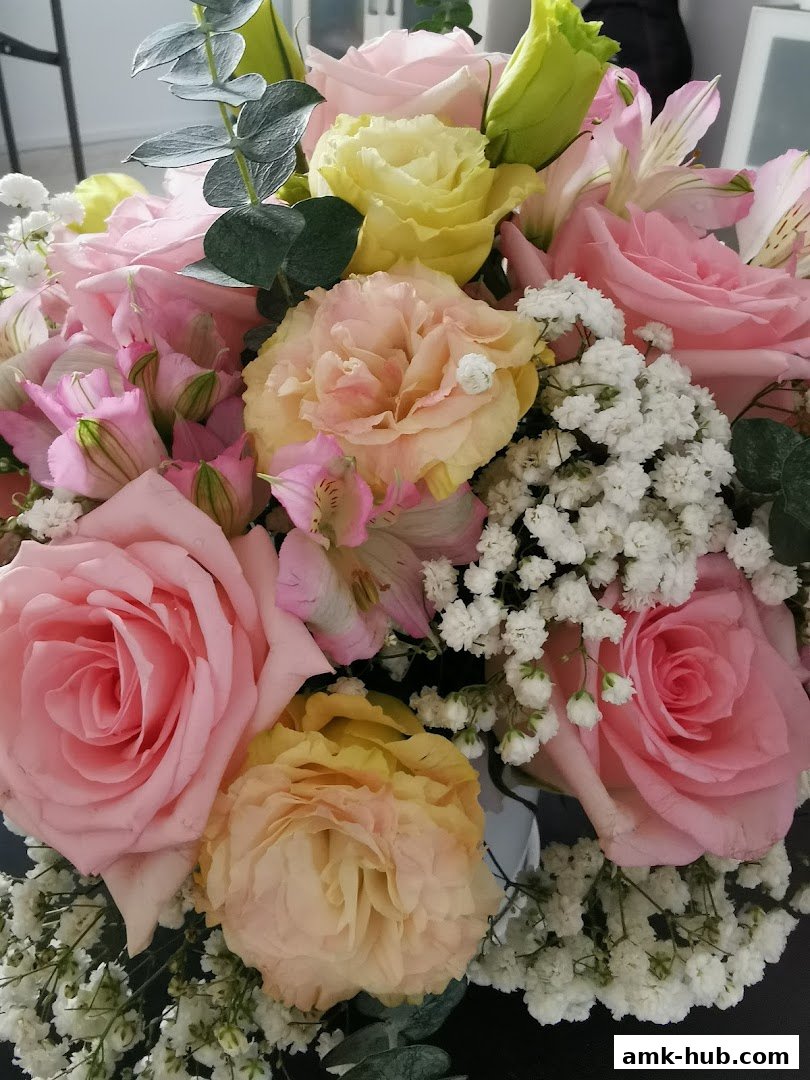 A beautiful bouquet of pink roses, yellow lisianthus, and baby's breath with eucalyptus leaves.