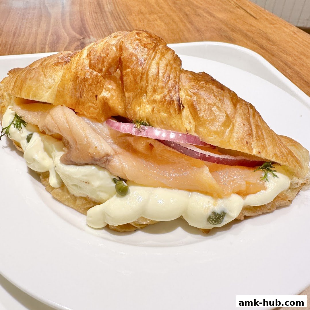 A delicious salmon and cream cheese croissant sandwich with red onion and capers.