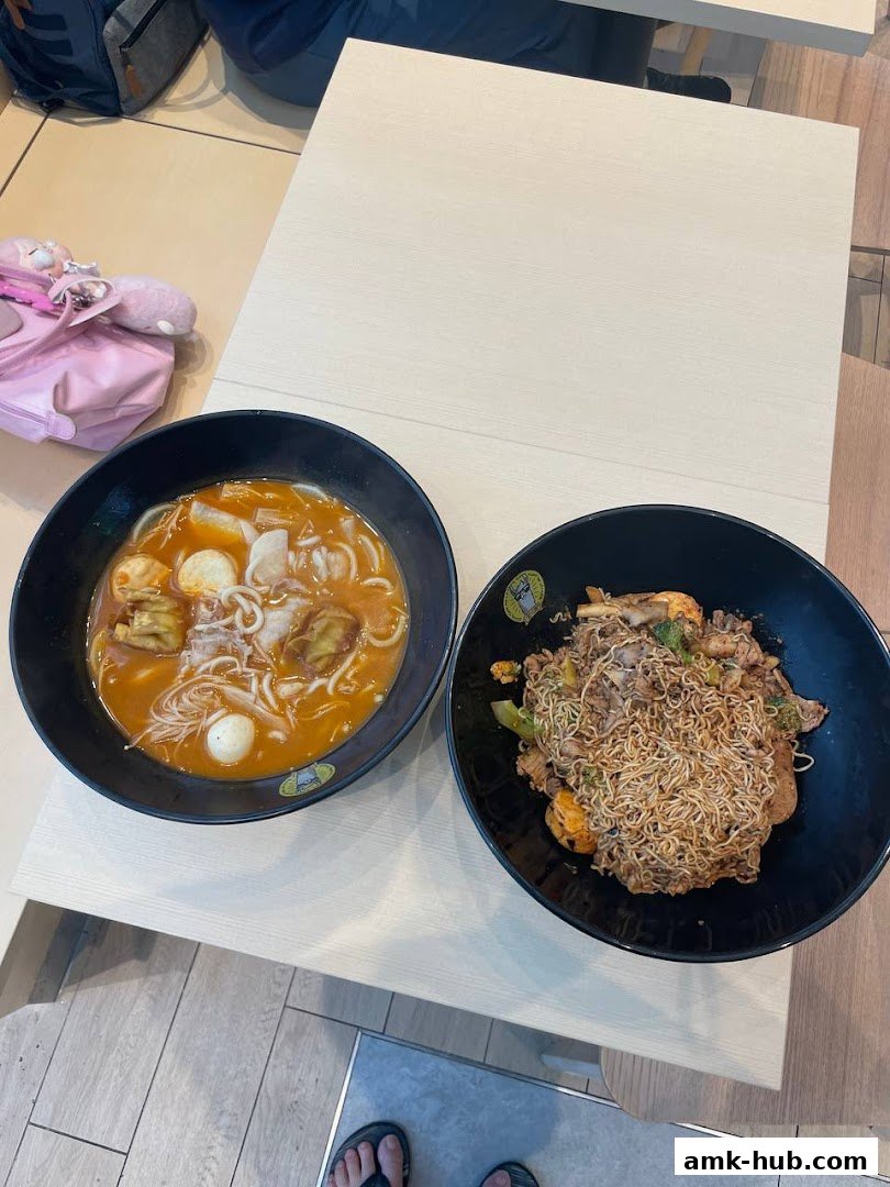 Two bowls of delicious noodles, one in broth and one stir-fried, served on a table.