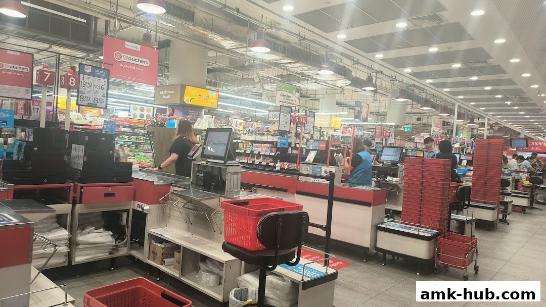 Interior view of a FairPrice Xtra supermarket checkout area with staff and customers.