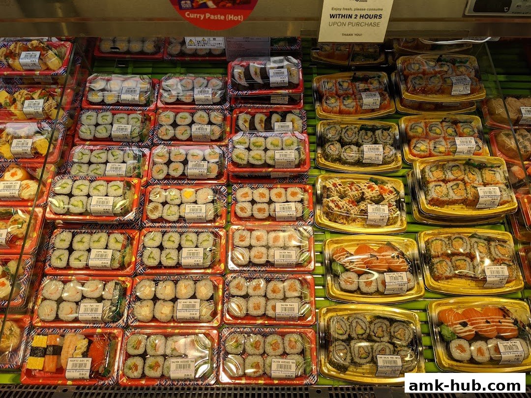 A display of various pre-packaged sushi rolls and other Japanese food items.