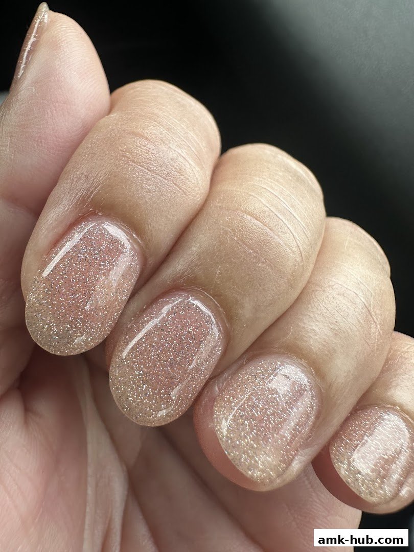 Close-up of a hand with beautifully manicured nails featuring a subtle glitter polish.