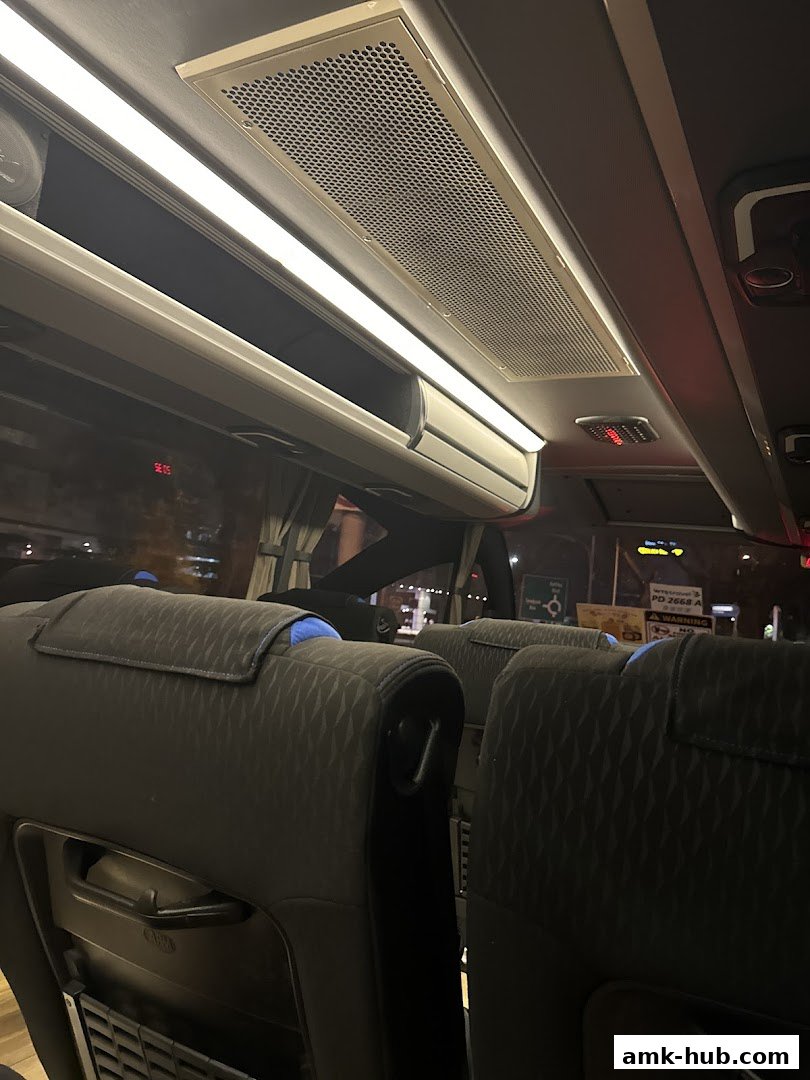 Interior view of a bus with comfortable seating and overhead compartments.