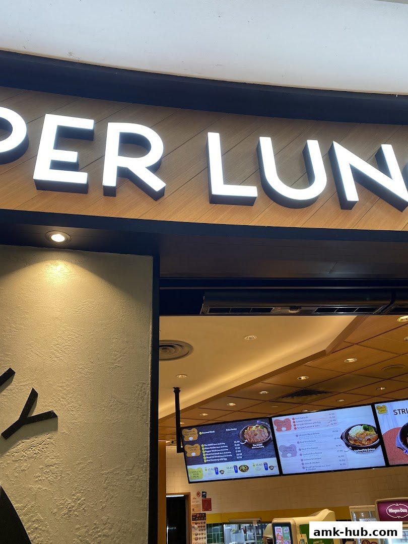 The illuminated sign for Pepper Lunch restaurant above a display of menu items.