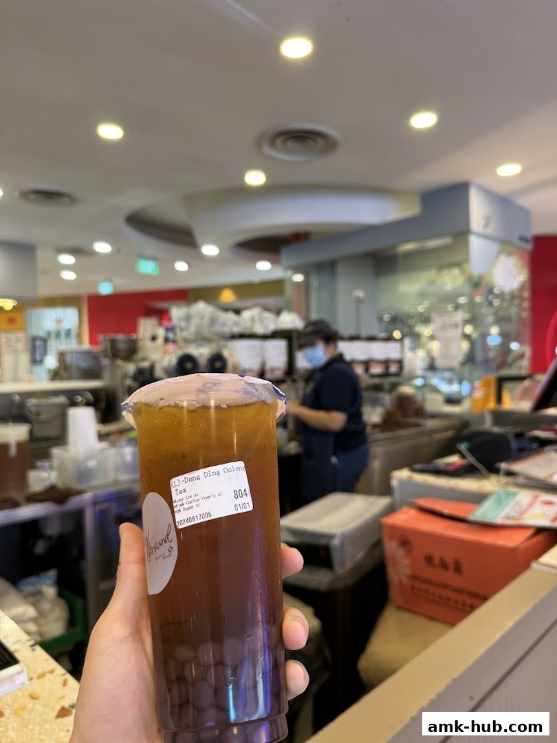 A hand holds a bubble tea drink with a label from Playground by PlayMade.