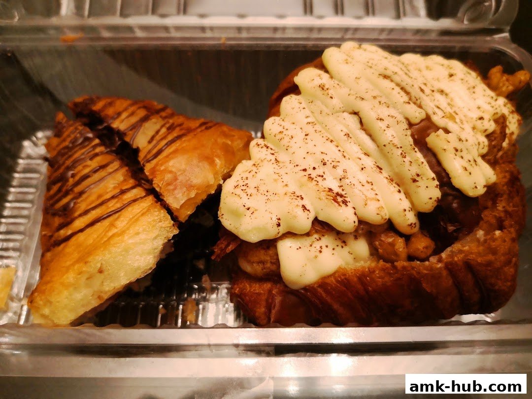 A close-up of two delicious pastries, one drizzled with chocolate and the other topped with creamy sauce.
